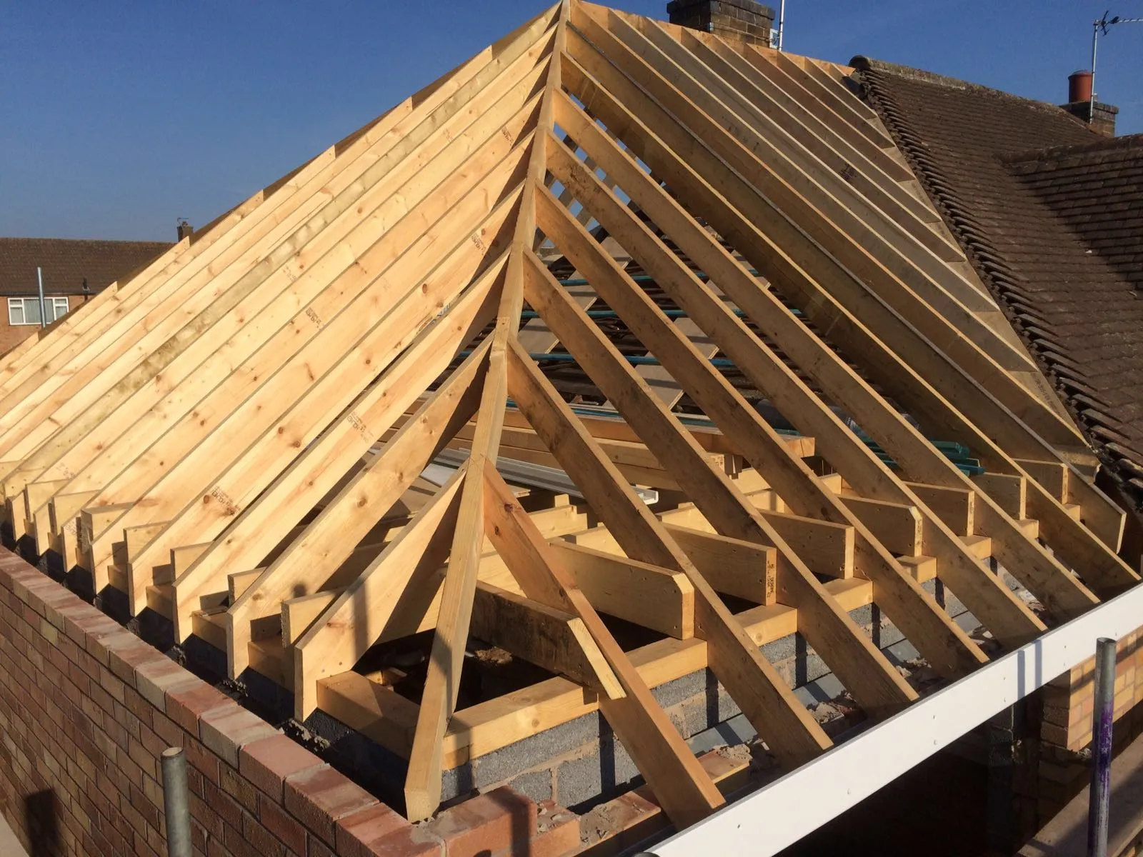 Roof framing in progress showing joists and trusses installed by hand 